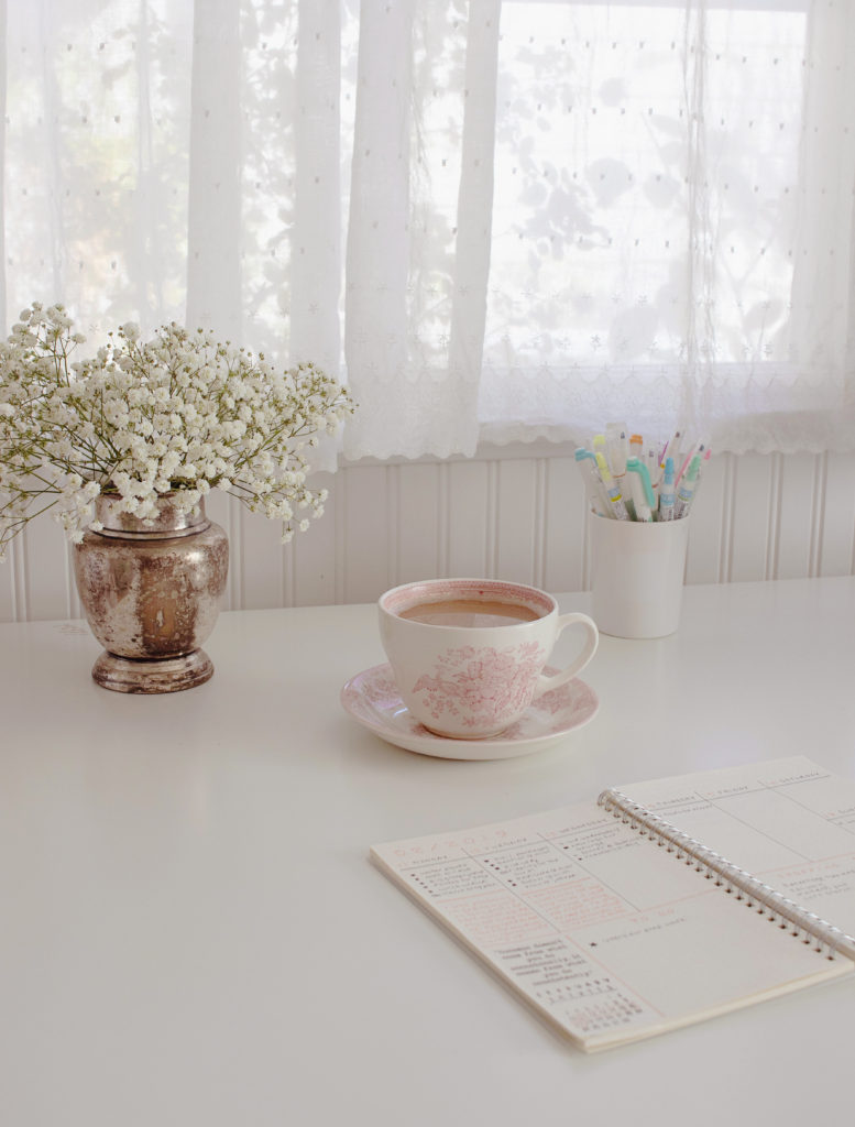 White desk with flowers and pink tea cup